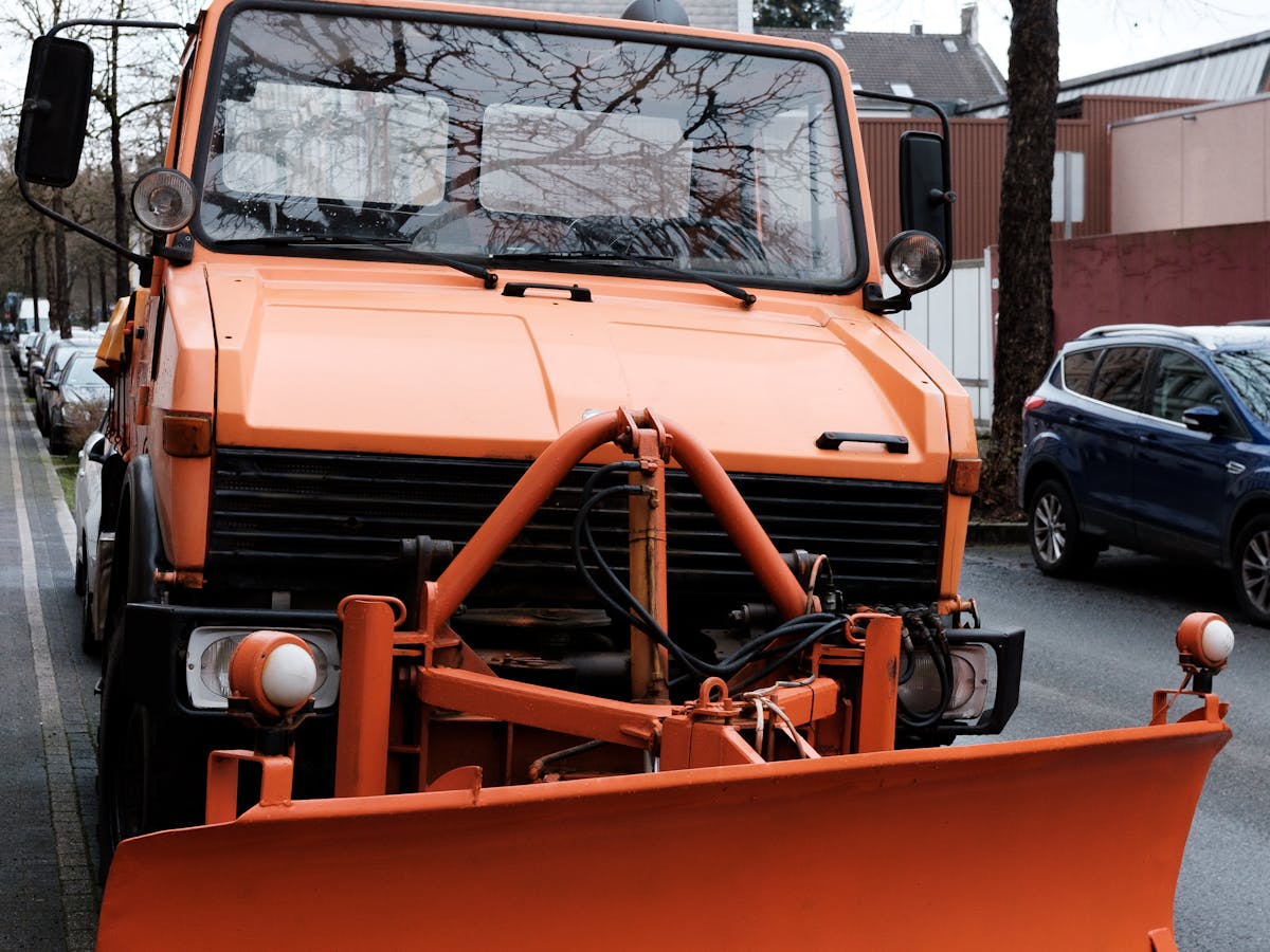 Orange snowplow truck sanding a lot for winter ice control